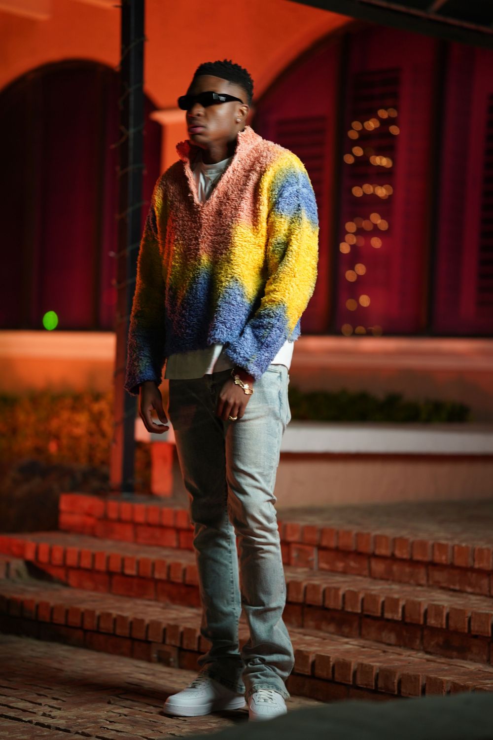 A stylish street fashion photo showing a vibrant color-block sweater and light denim jeans.