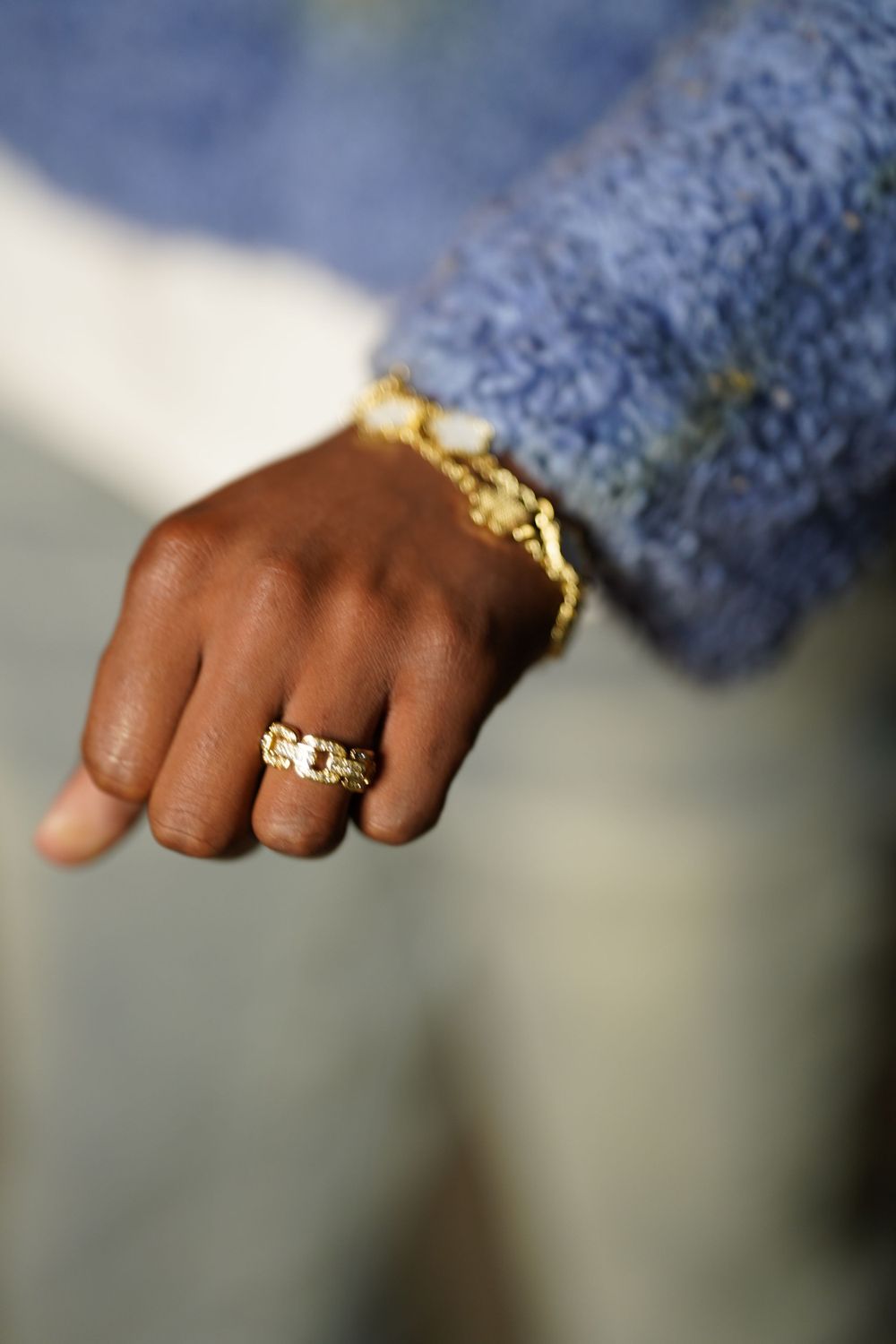 Close-up shot of hands adorned with gold rings against a blue textured background.