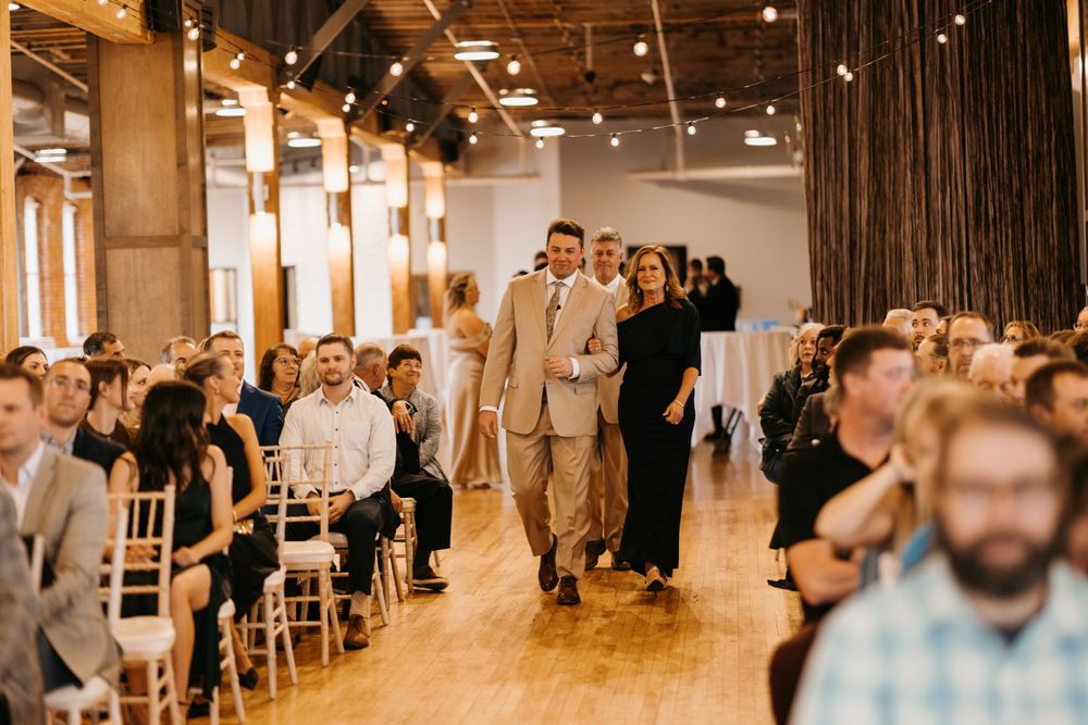 A couple walks down the aisle together during a wedding ceremony in a modern industrial venue.