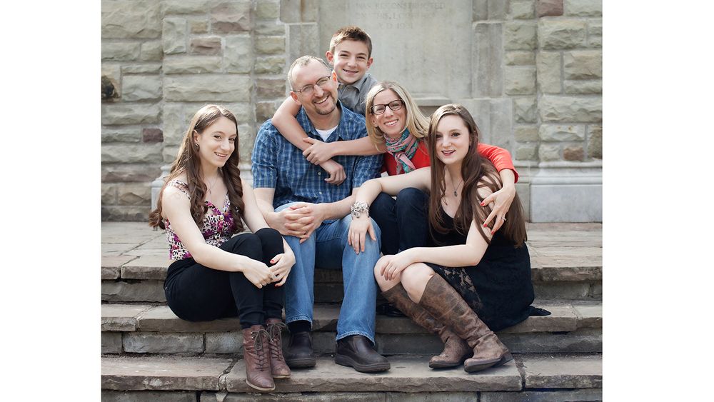 Family portrait of multiple generations sitting together on stone steps outdoors.