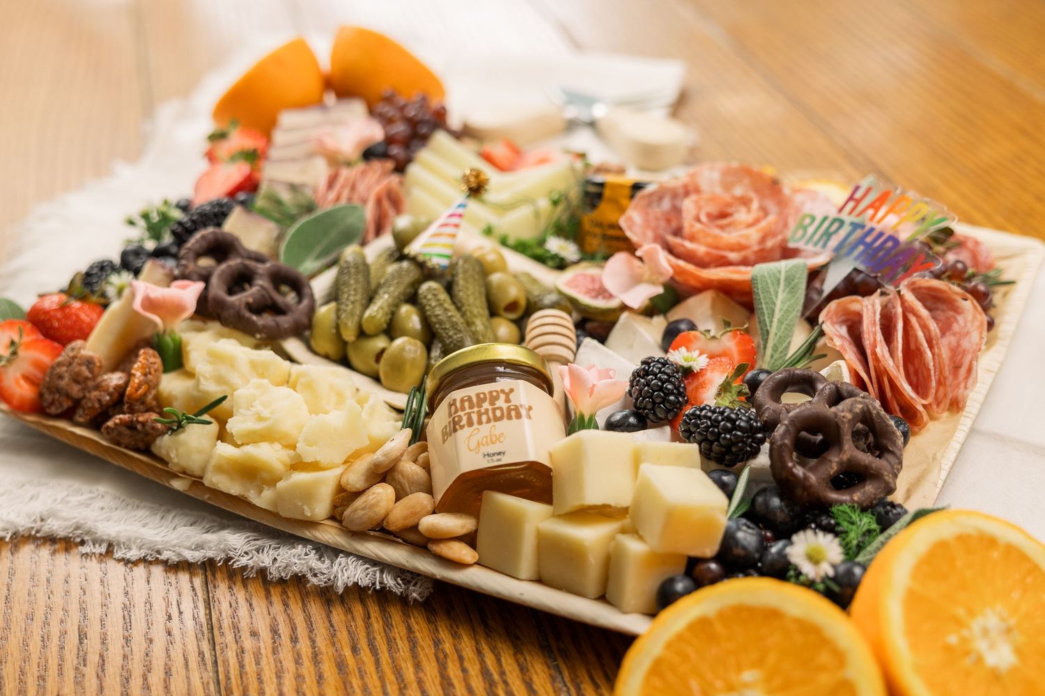Gourmet charcuterie board with meats, cheeses, fruits, nuts and olives arranged on wooden surface.