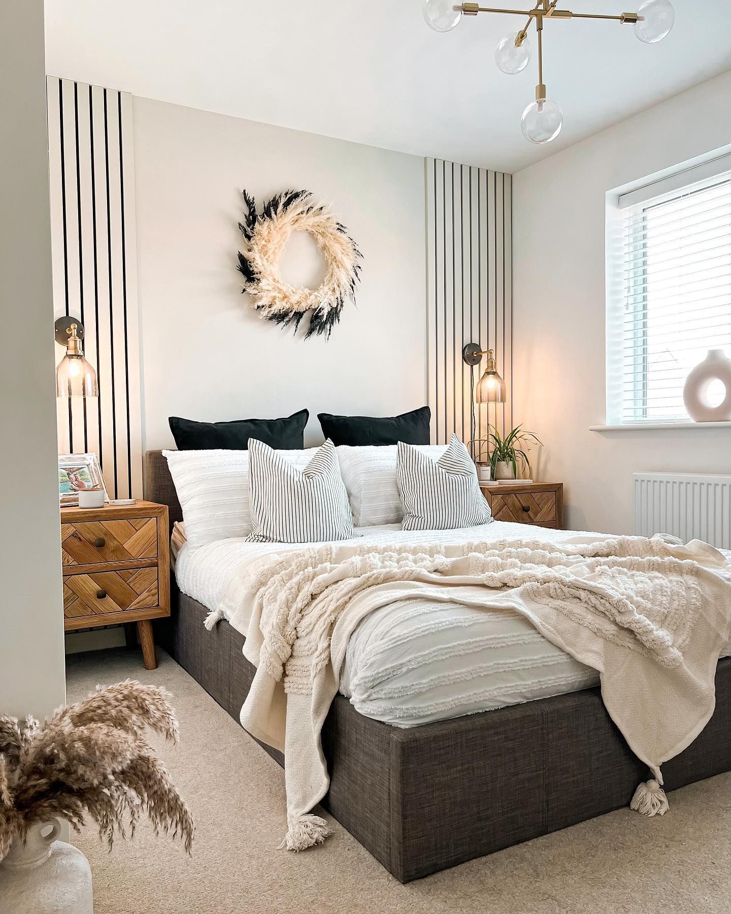 Cozy neutral bedroom with decorative wreath, wooden furniture and textured bedding.