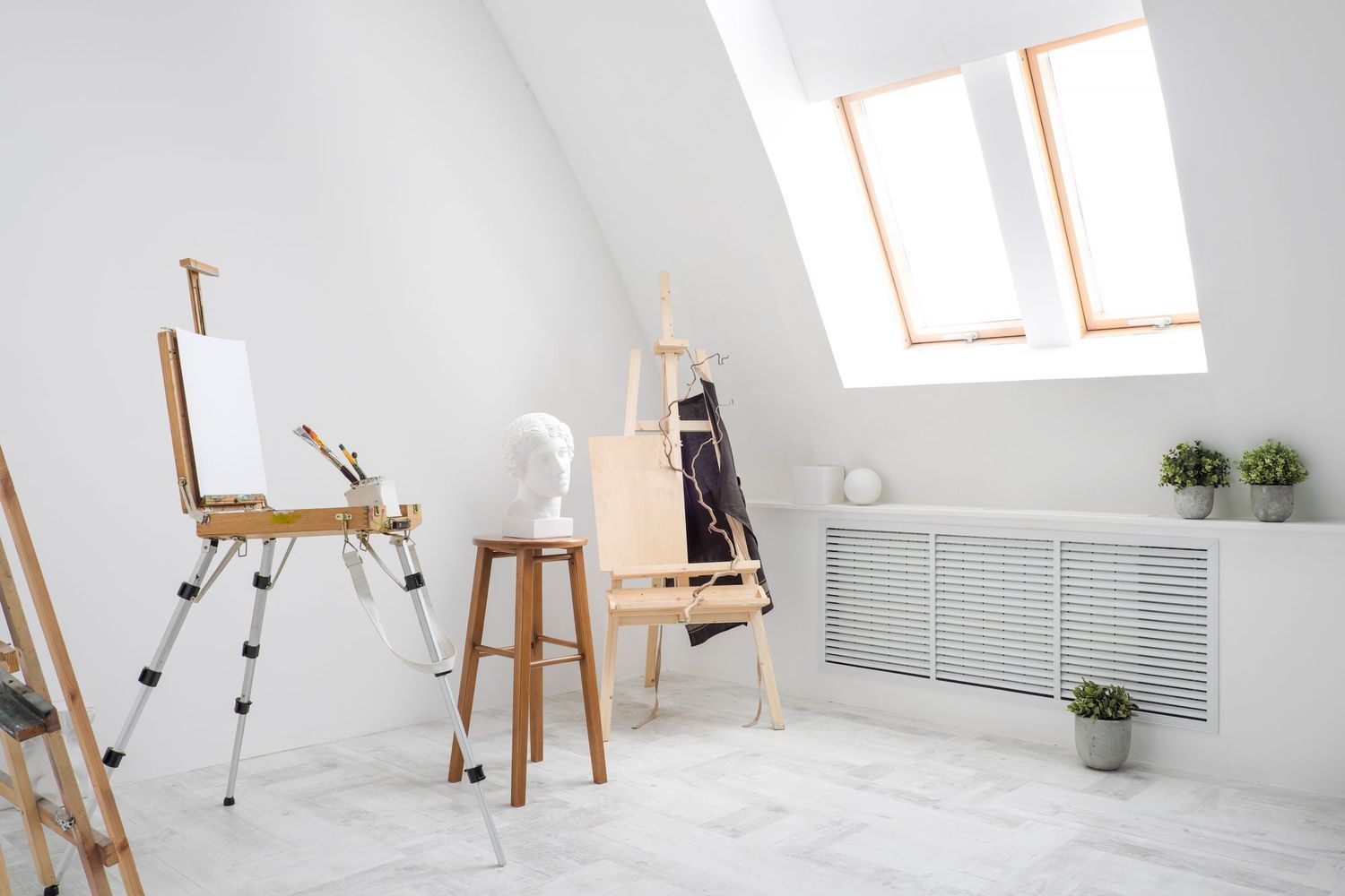 Minimalist white art studio space with easels, stools and skylights.