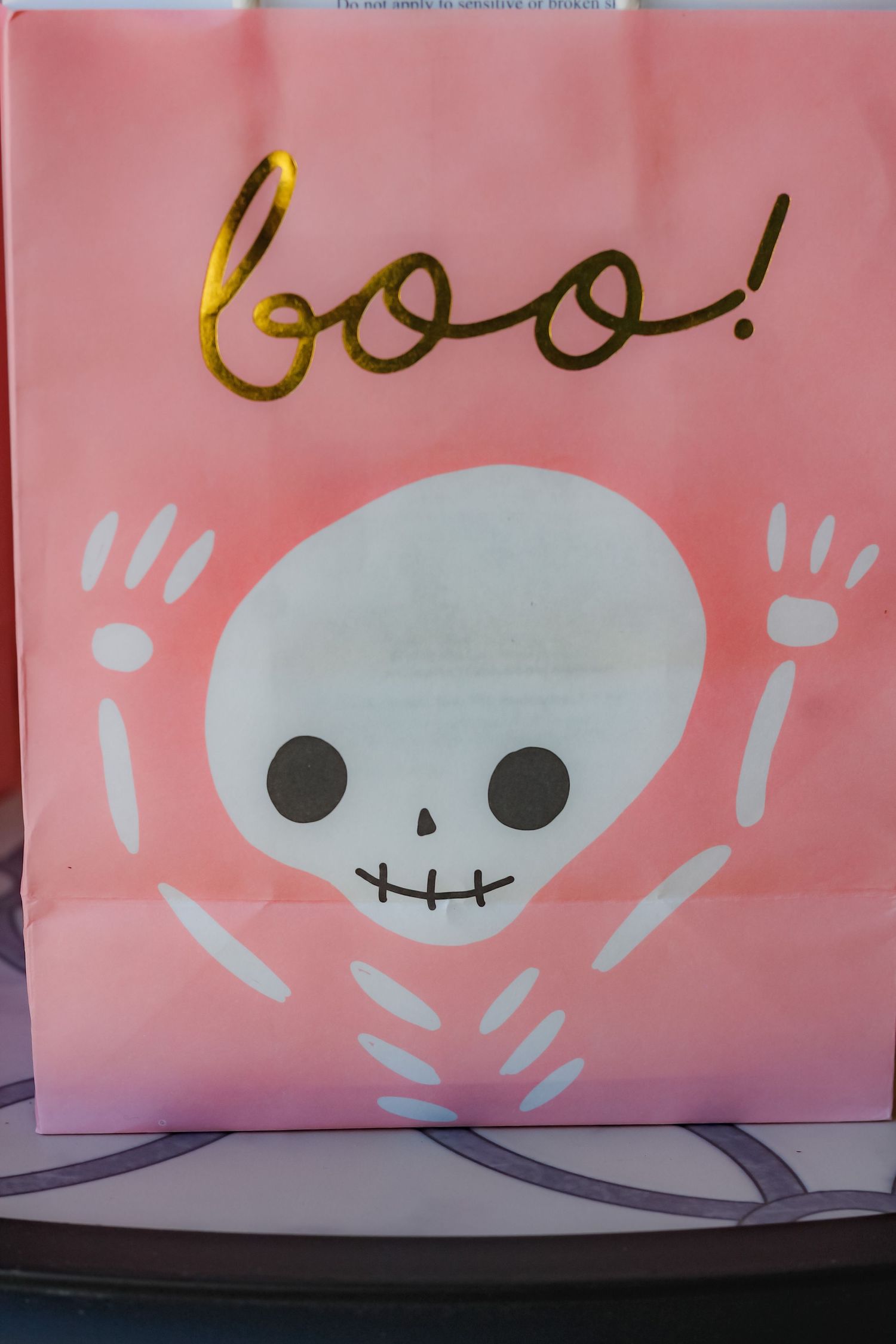 A cute cartoon skeleton drawing with 'boo!' text on a pink background.
