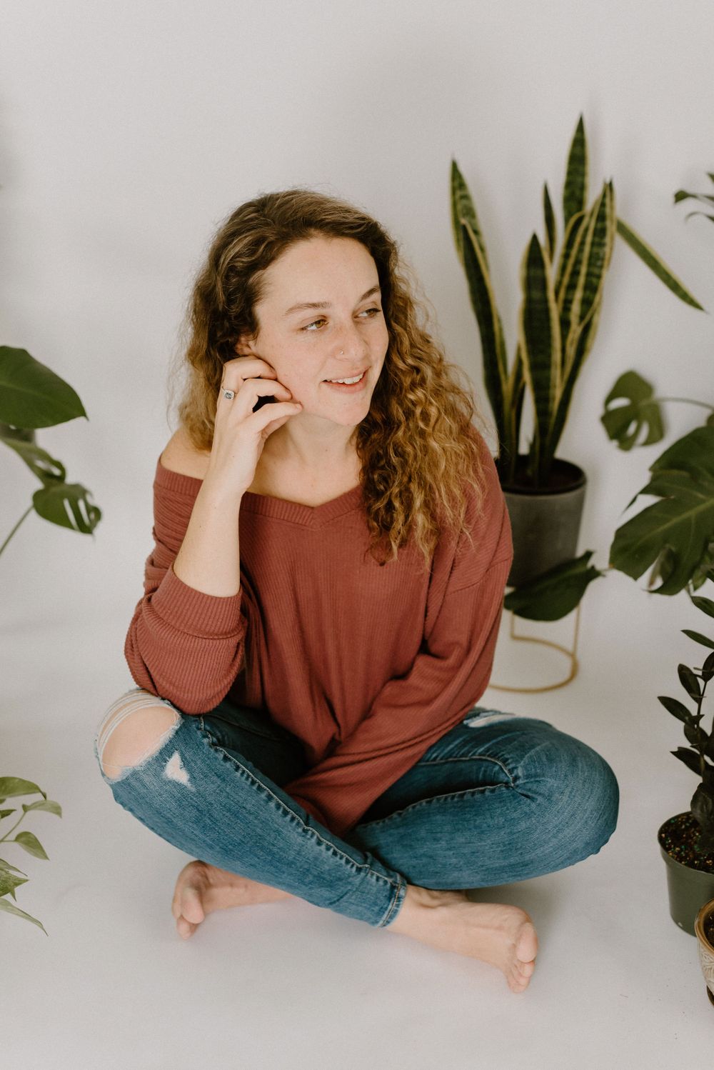 Gigi Hartwick sitting on the floor in home studio smiling looking away during branding shoot.