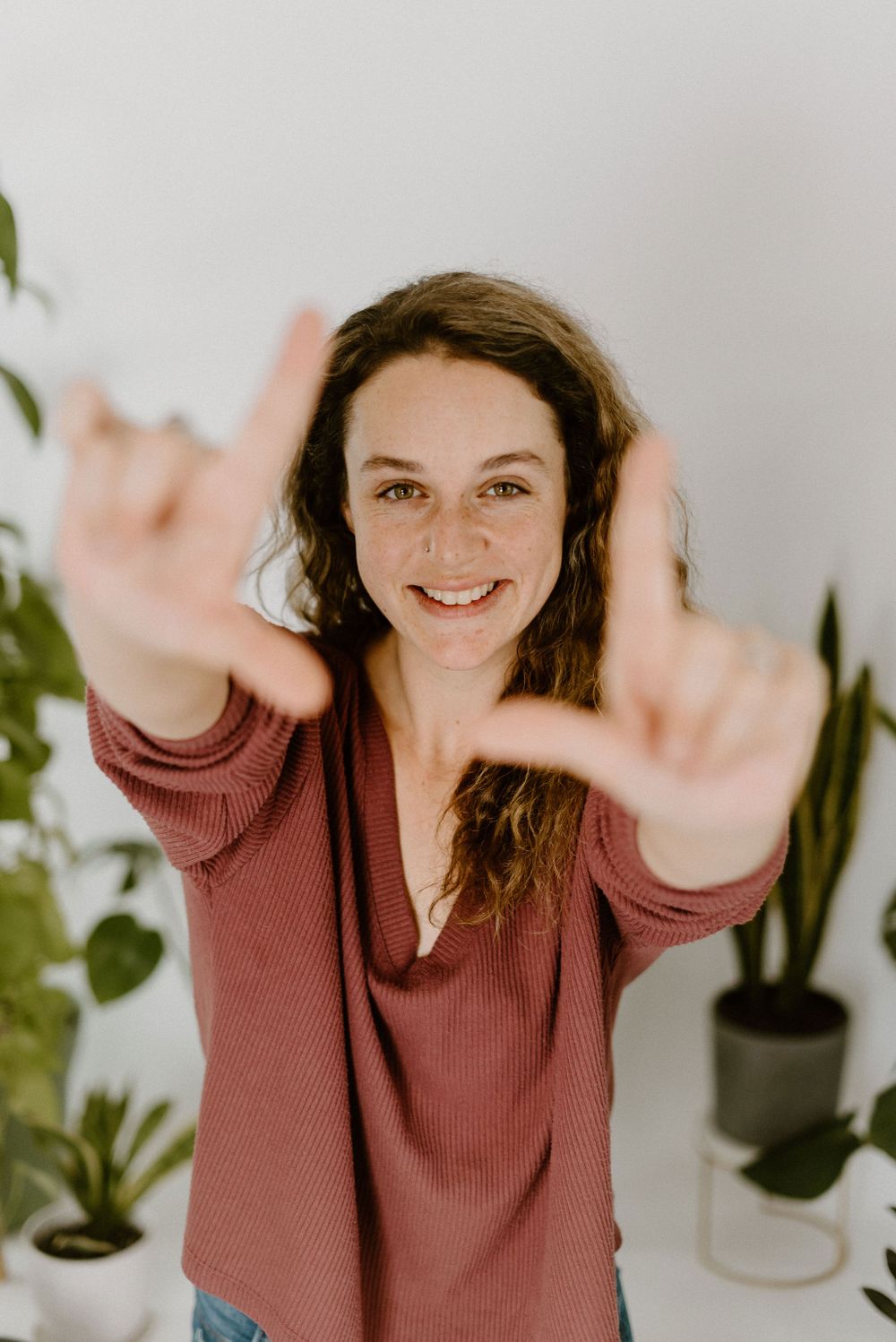 Gigi Hartwick making a fake camera with her fingers to frame her face for portrait.