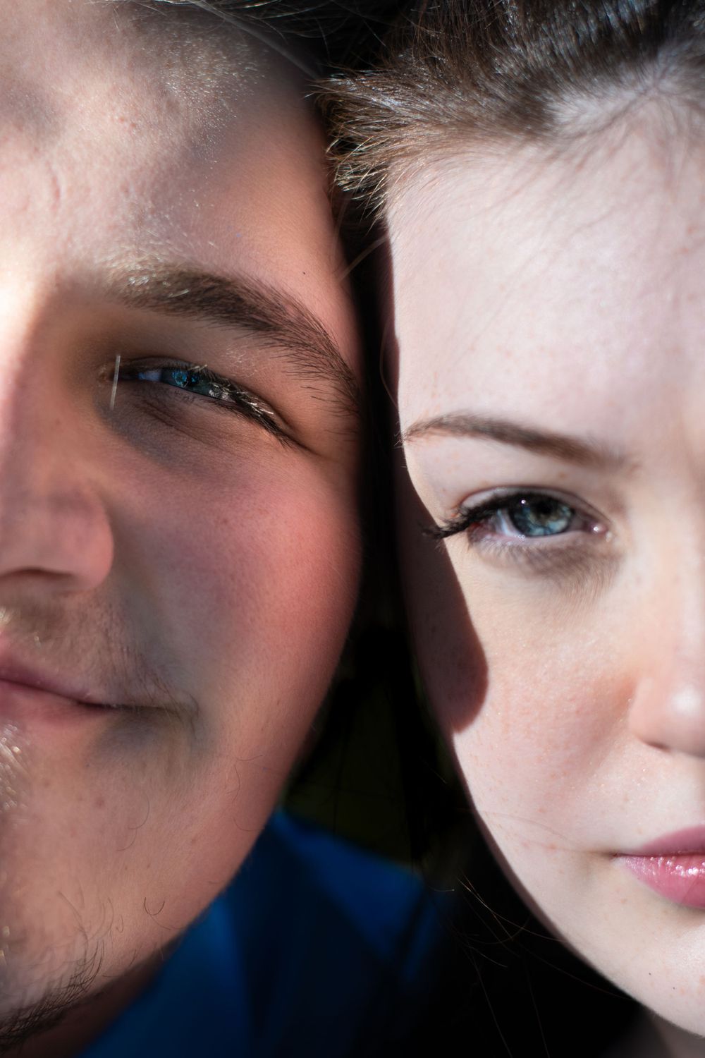 Artistic close-up portrait showing partial faces against dark background.