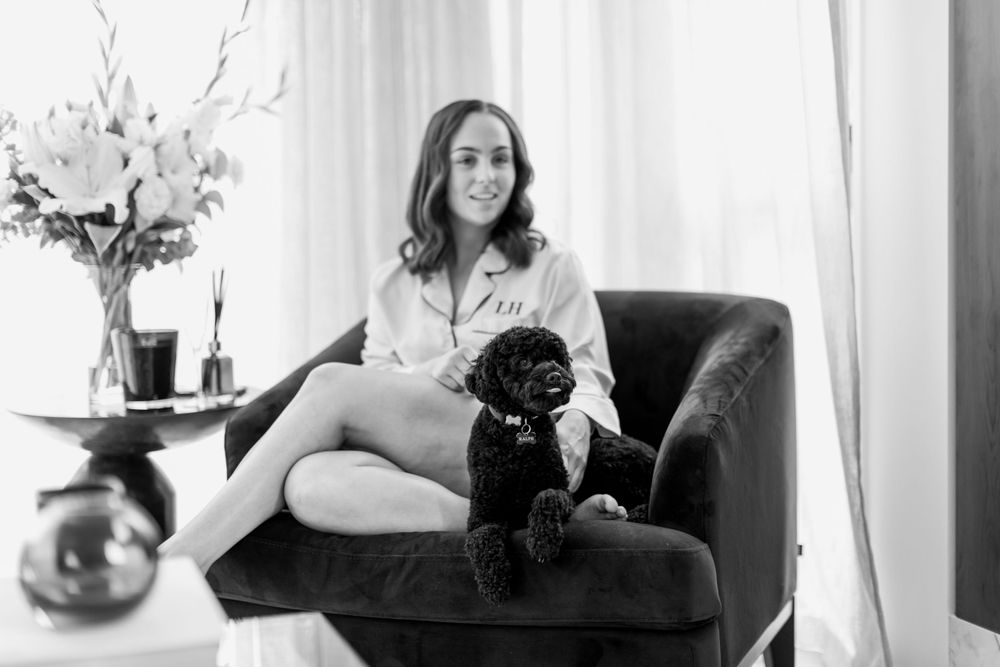 A relaxed moment captured in black and white of a person sitting with a small black dog.