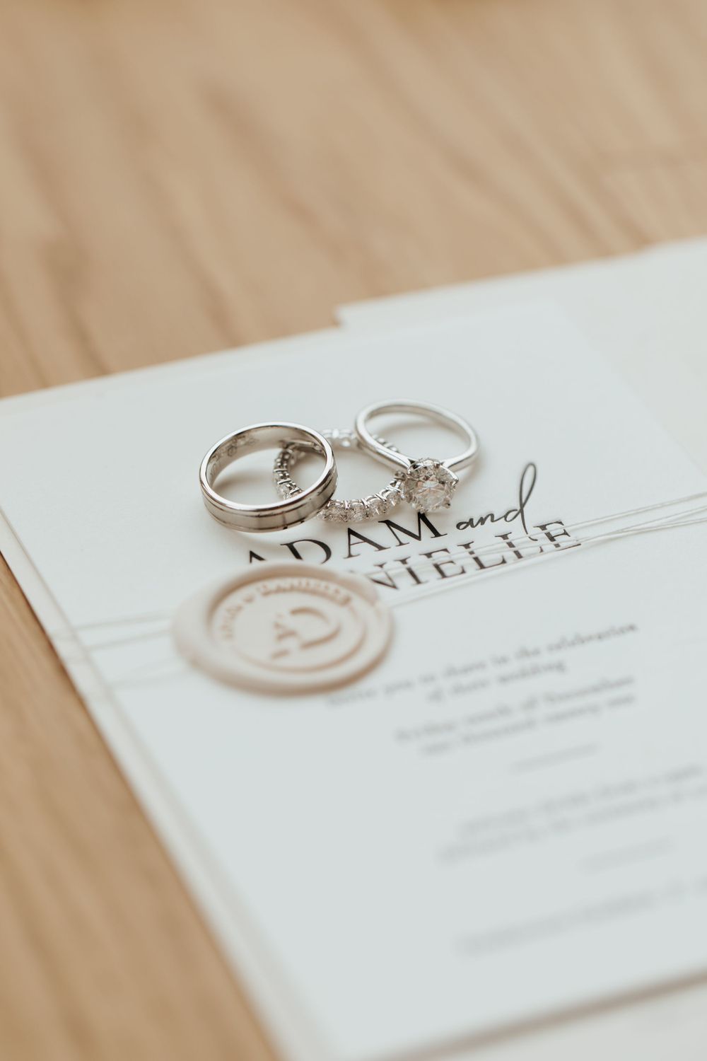 Wedding rings and wax seal on an elegant white invitation suite.