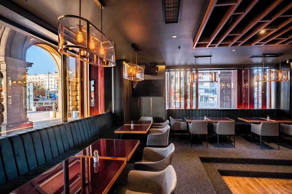 Upscale restaurant interior with navy blue booth seating, ambient lighting, and wooden accents.