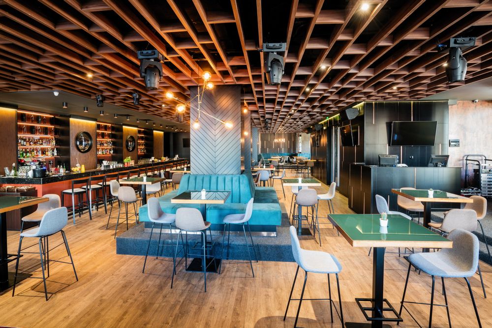 Stylish dining area featuring colorful booth seating, geometric ceiling patterns, and modern lighting fixtures.