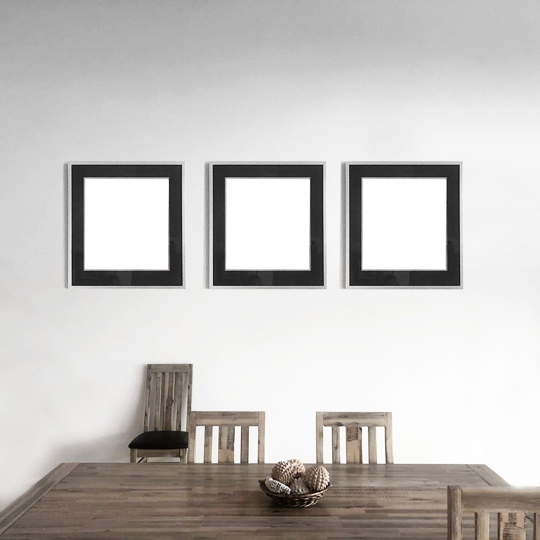 Three black square frames aligned horizontally above wooden dining table and chairs in minimalist room.