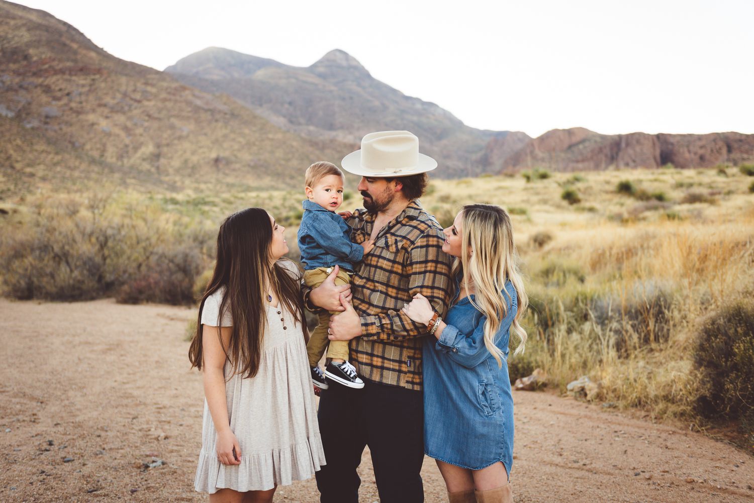 Candid family interaction in a desert landscape with mountains in the background.