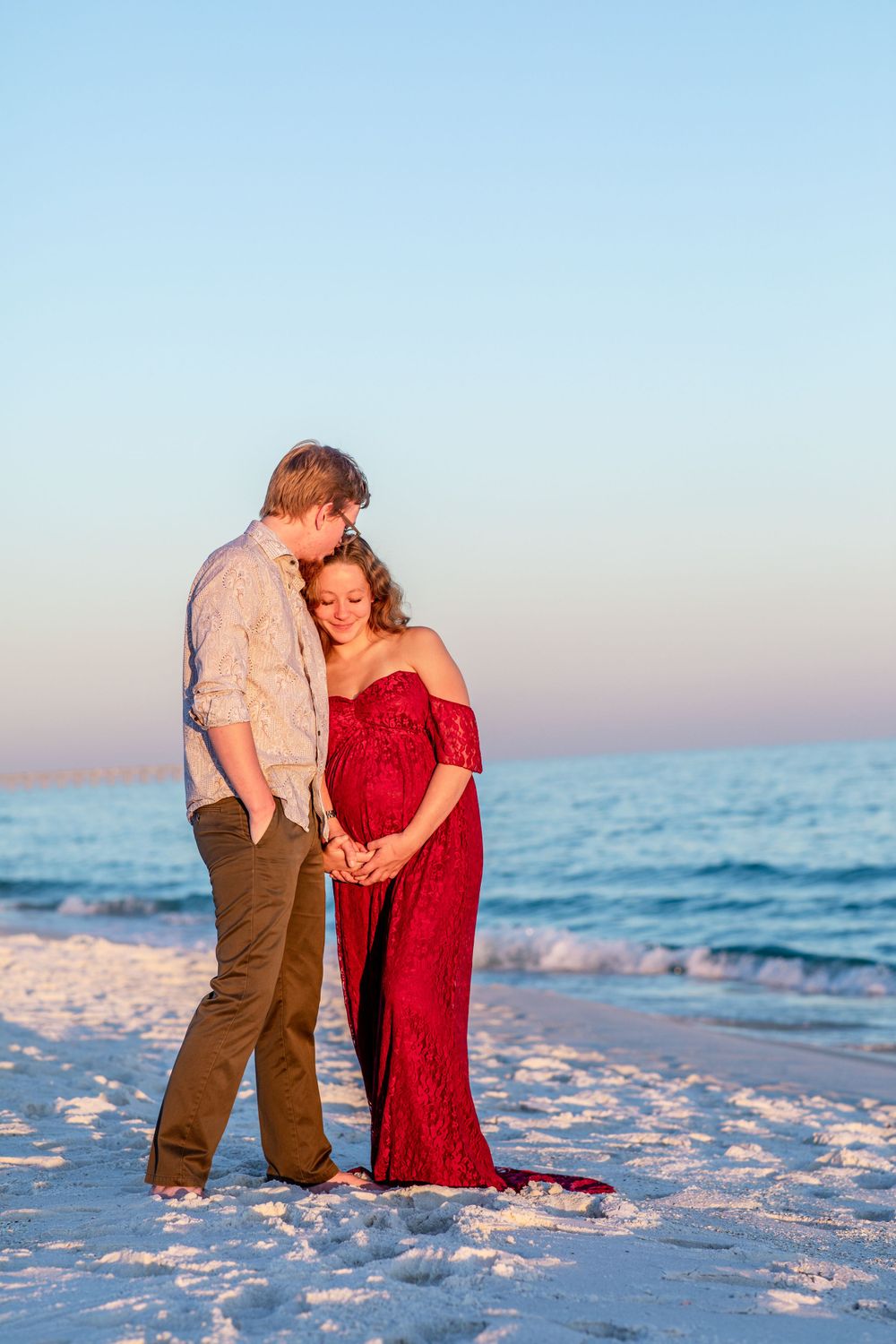 Couple shares an intimate moment on a beach at sunset.
