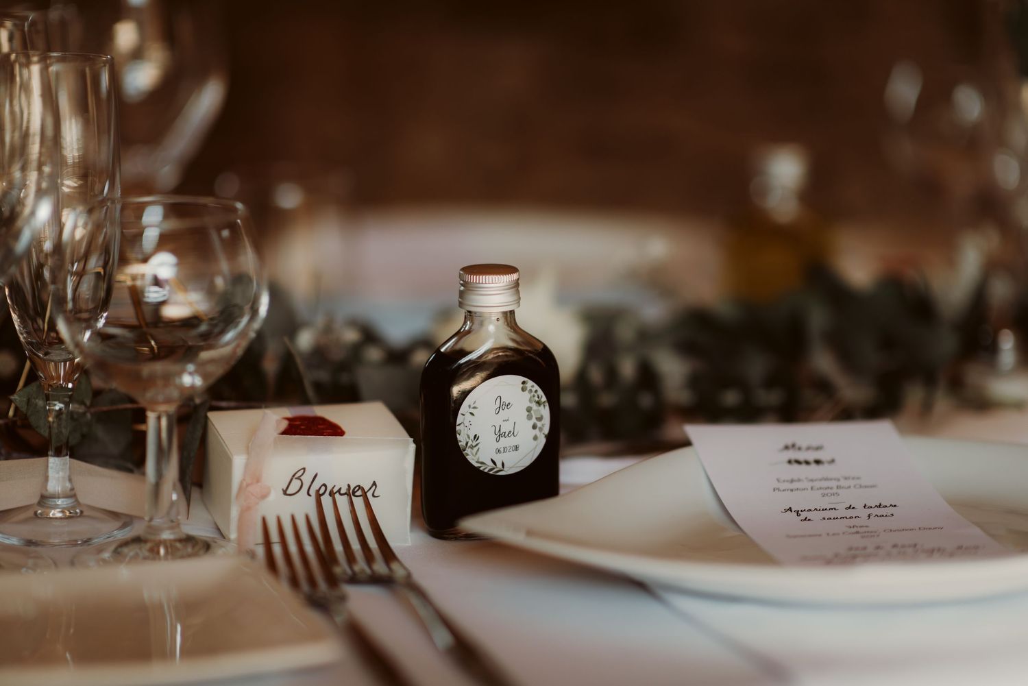 Elegant table setting with wine glasses and vintage bottle on rustic wooden surface.