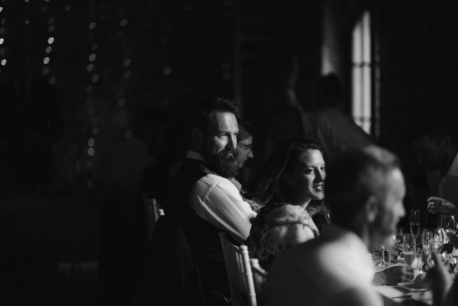 Candid black and white shot of wedding guests enjoying the reception.