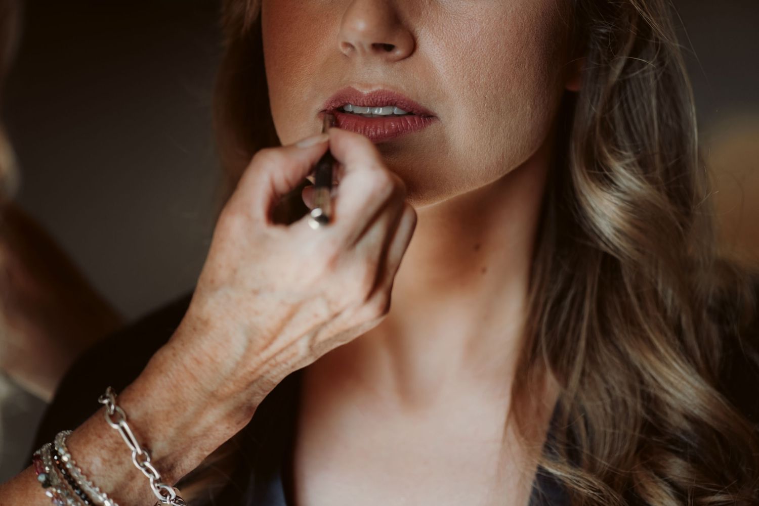 Close-up shot of makeup artist applying lipstick during bridal preparation.