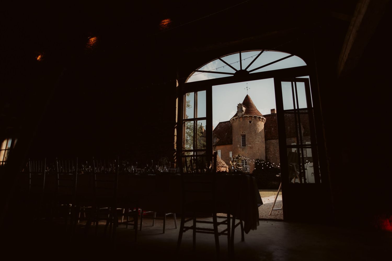 Dark interior room with arched doorway framing view of castle-like building in distance.