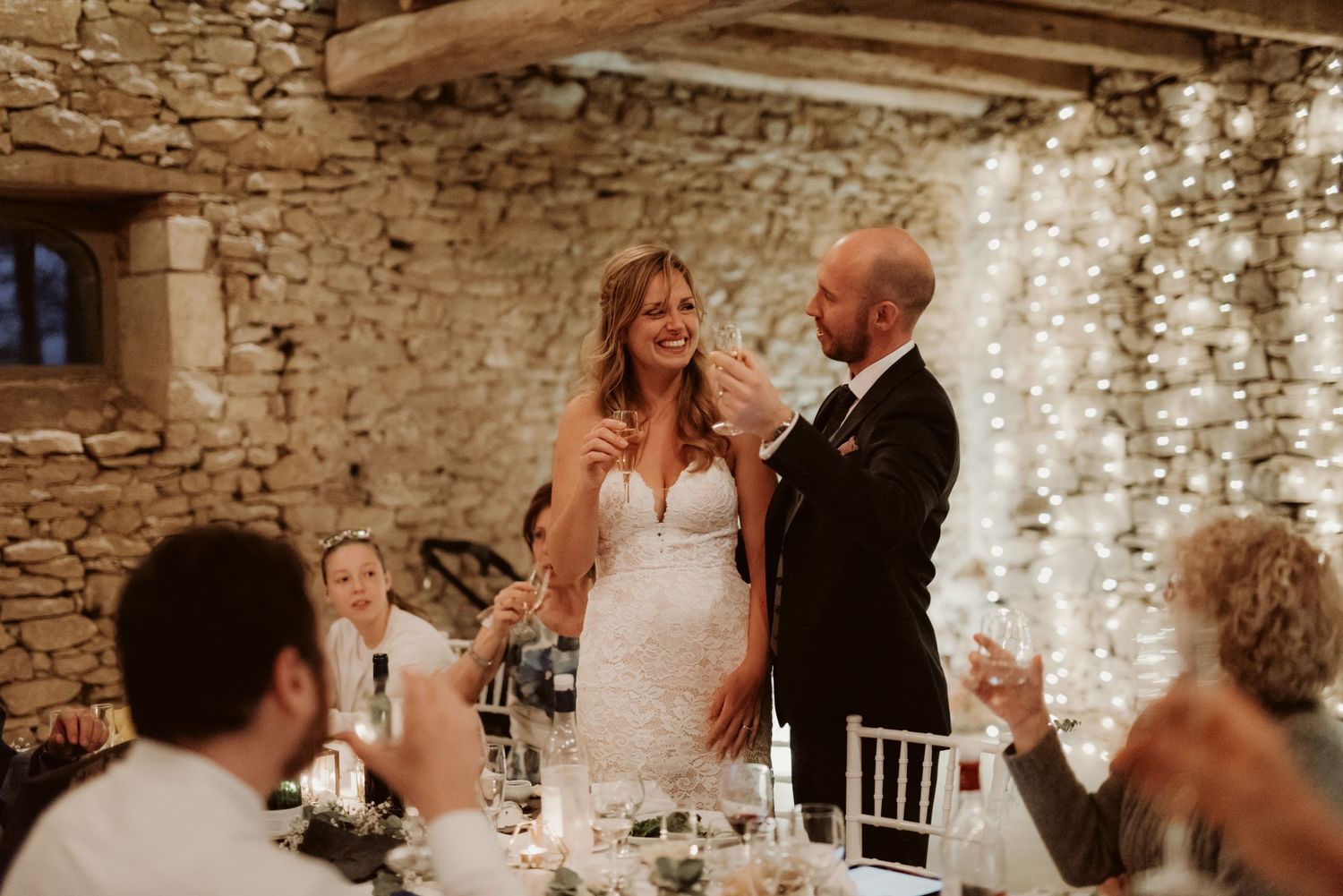Couple shares a special moment during wedding reception speeches in a rustic venue.
