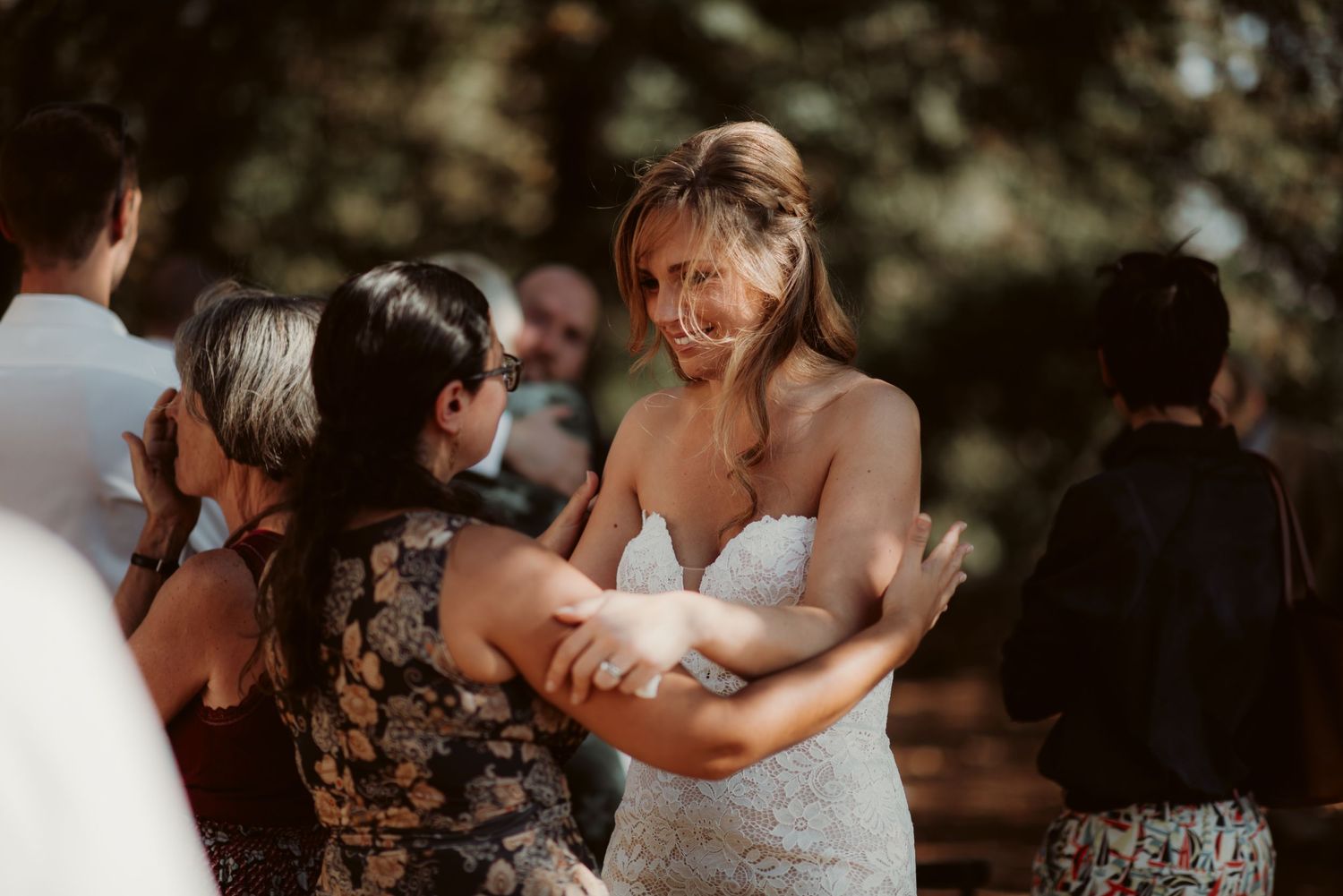 Wedding guests share warm embraces during an outdoor celebration.
