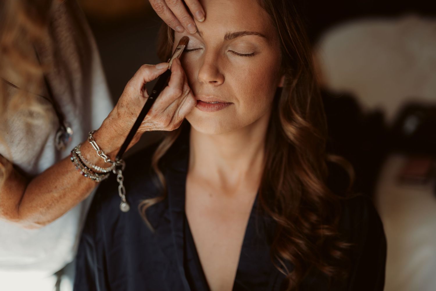 Close-up of makeup application during wedding preparation in warm light.