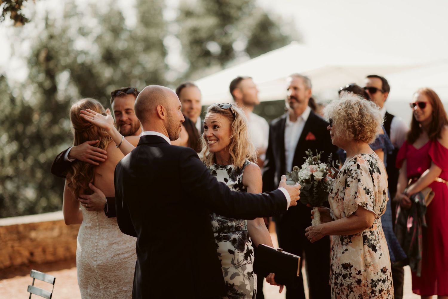 Wedding guests gather for a joyful celebration during an outdoor ceremony at sunset.