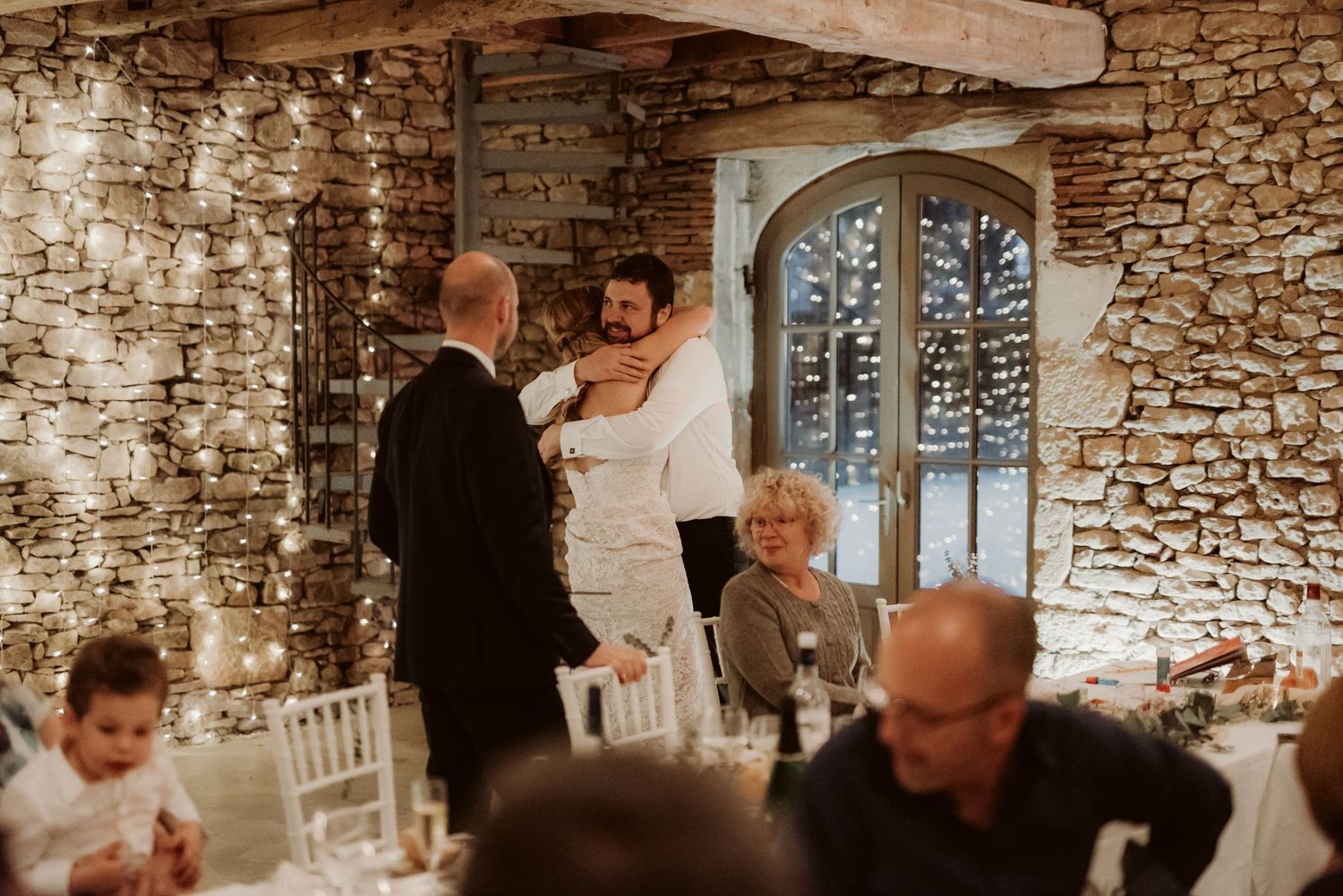 Intimate wedding reception moment in a rustic stone venue decorated with fairy lights.