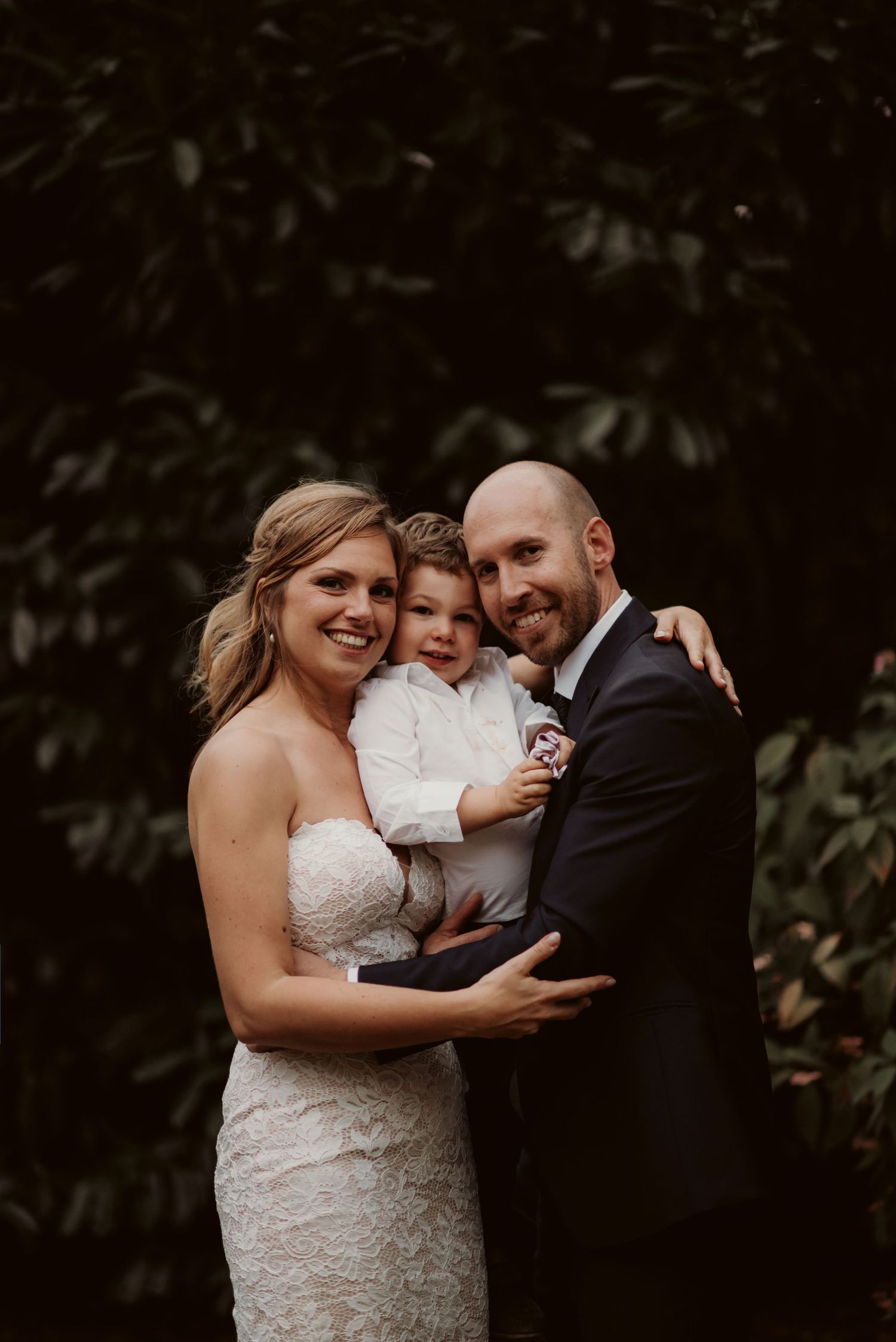 Heartwarming wedding portrait of family against lush garden background.