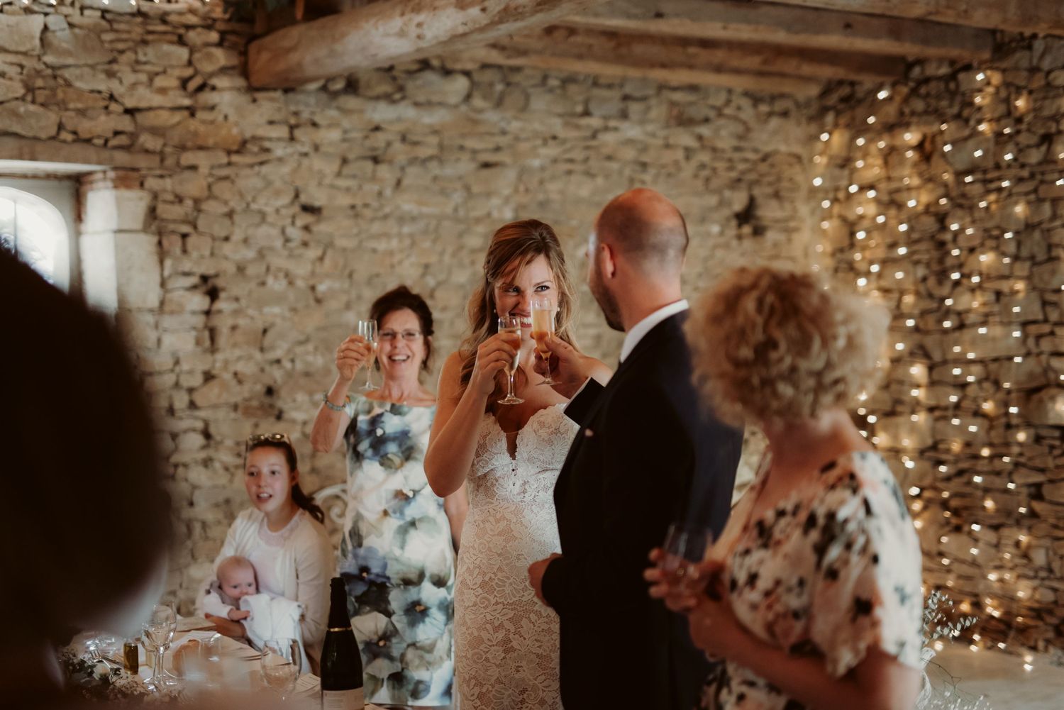 Wedding reception toasts in a charming rustic venue with fairy light decorations.