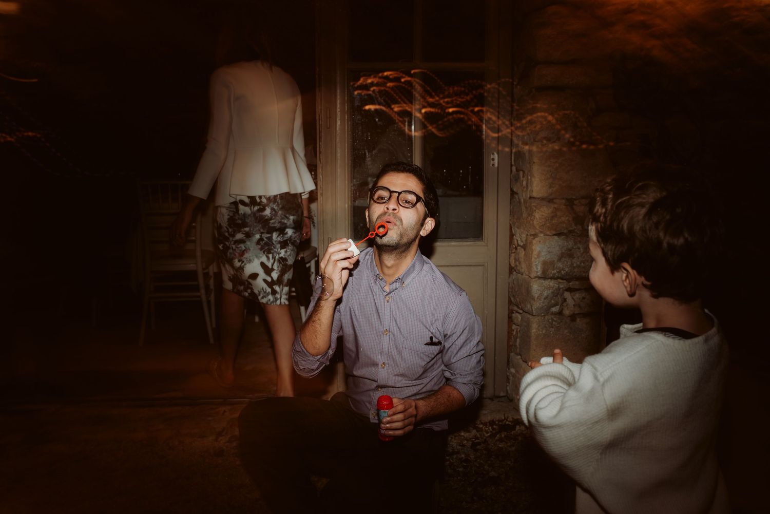 Friends enjoying conversation and drinks in a dimly lit room with ambient lighting.