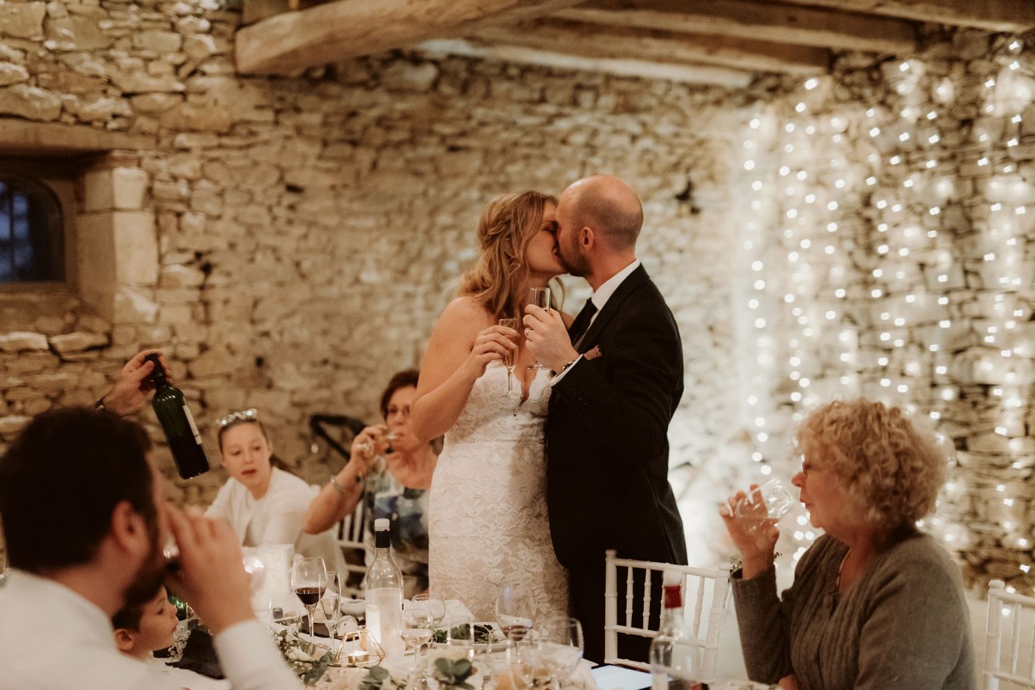 Wedding celebration reaches its peak during toasts in a romantically lit stone venue.