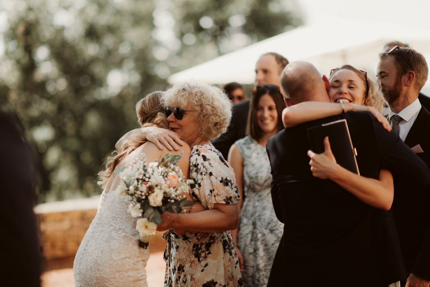 Emotional embraces are shared among wedding guests during an outdoor reception.