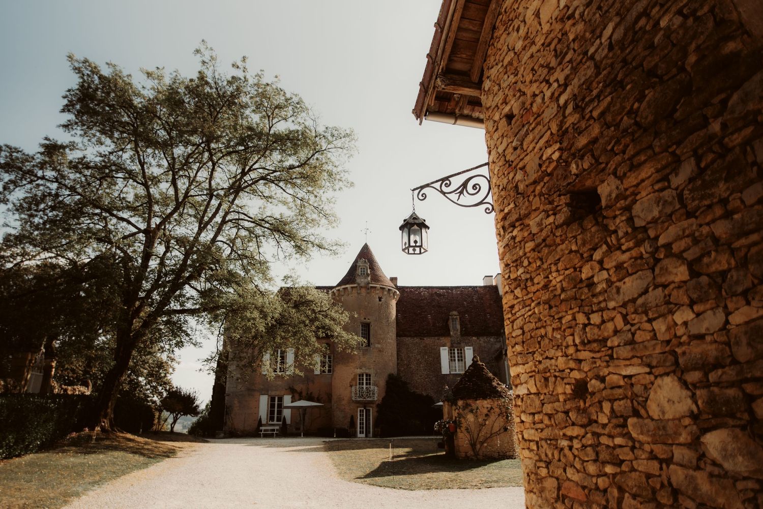 Stone castle-like building with turret and lantern visible along curved driveway.