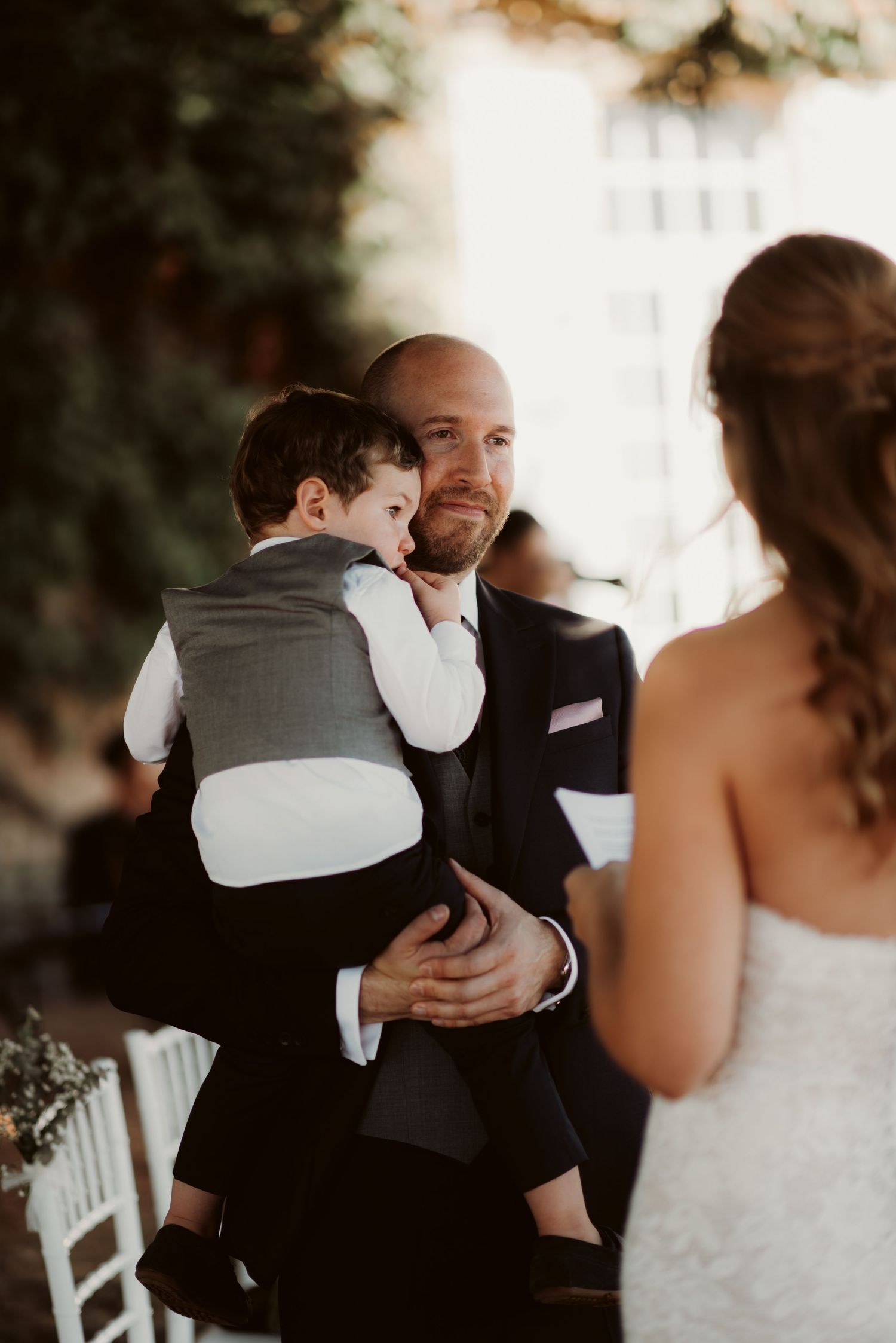 A tender moment during an outdoor wedding ceremony with a child embracing.
