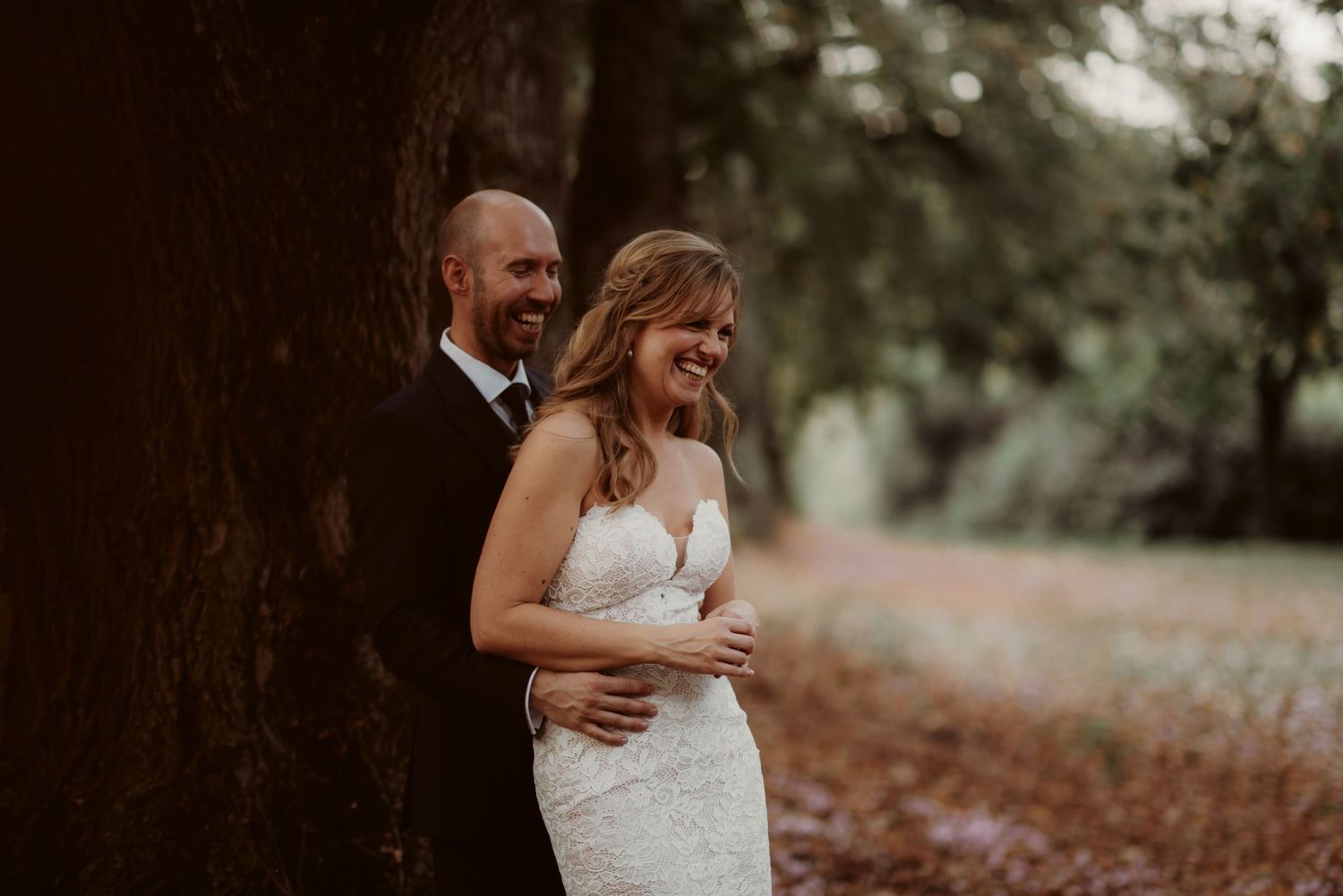 Romantic moment captured between couple against tree trunk in natural setting.