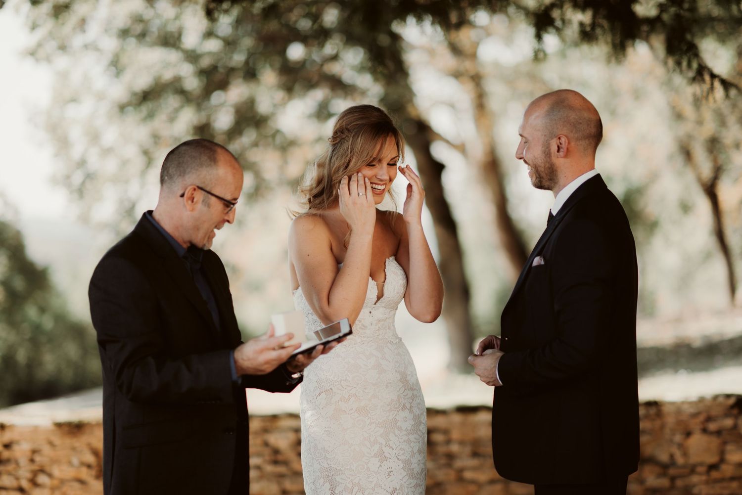 An emotional wedding ceremony moment with reactions of joy under tree shade.