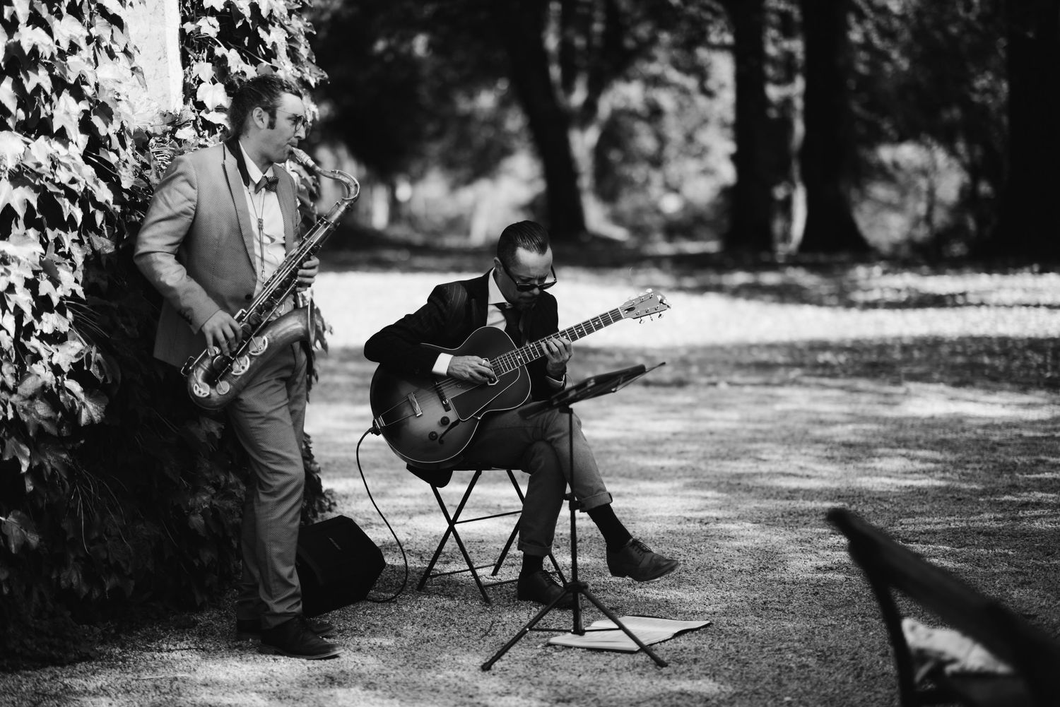 Musicians perform with saxophone and guitar during an outdoor event.