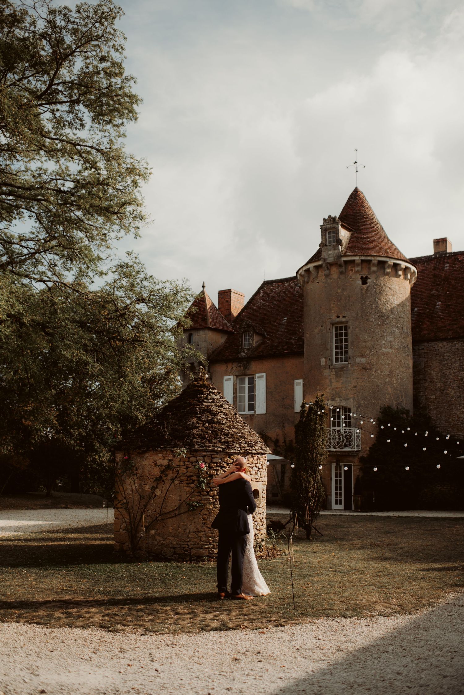 Romantic silhouette against a majestic French chateau with turret and string lights at dusk.