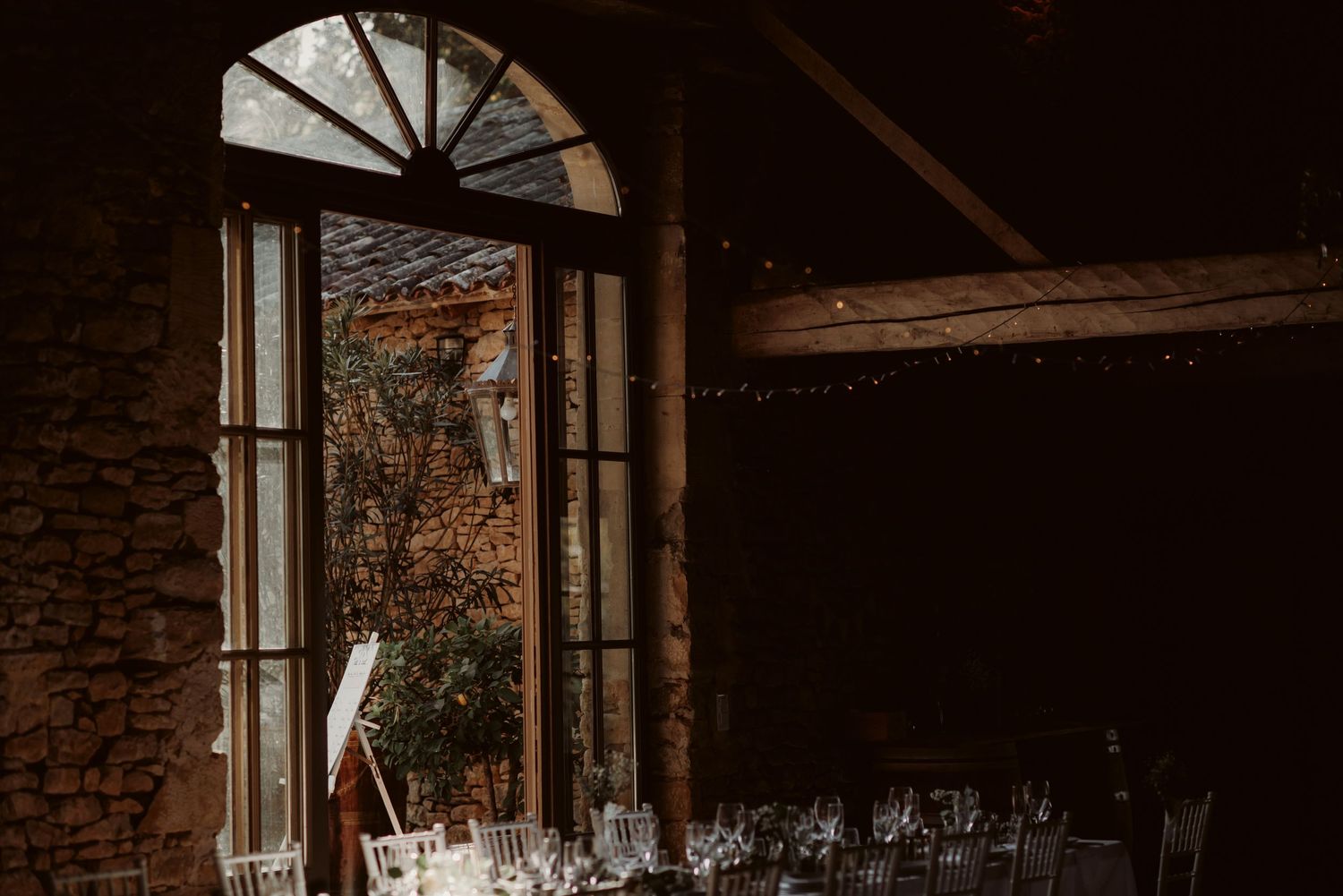 Wedding reception venue with arched window and elegant table settings.