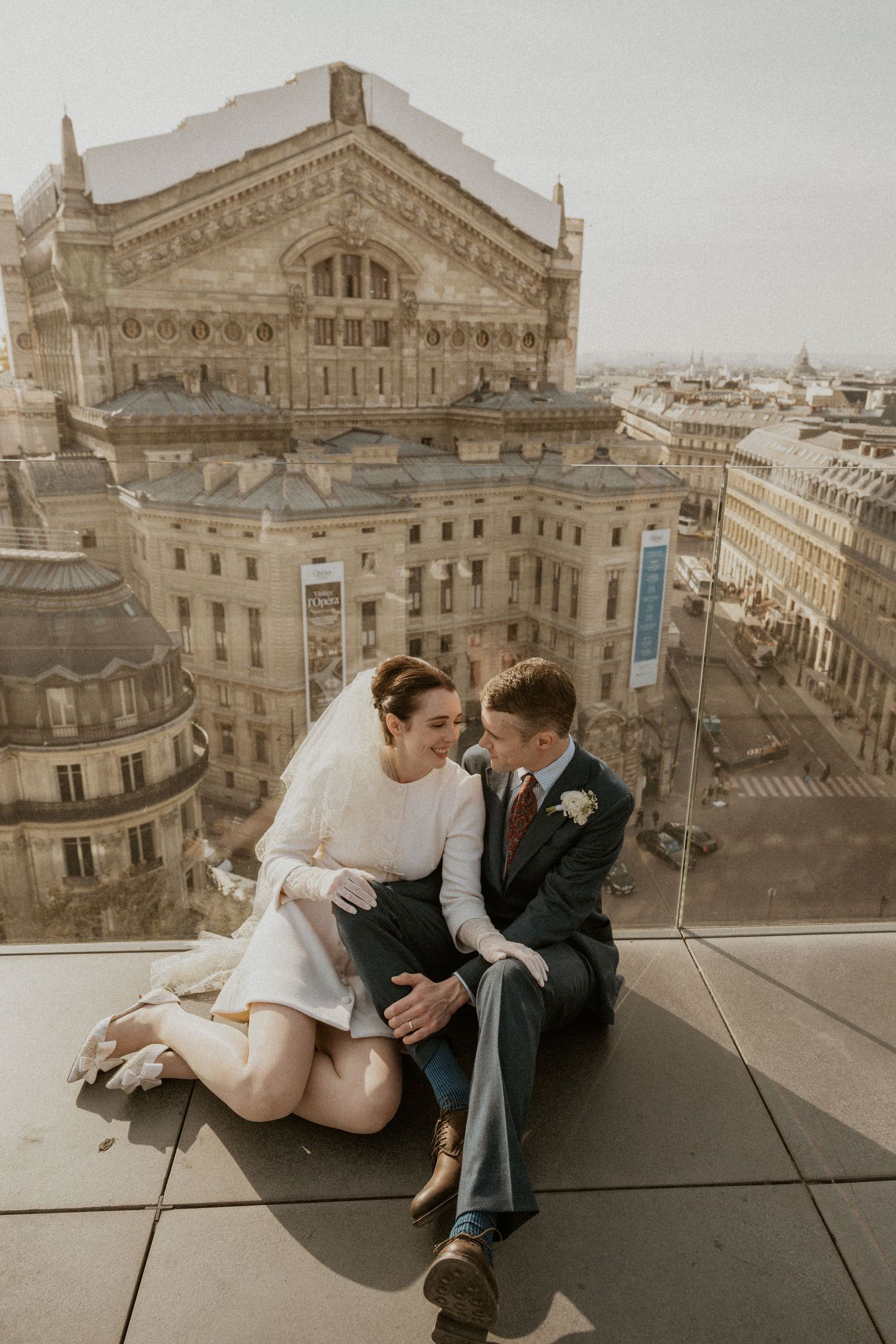 Intimate moment between couple on rooftop overlooking Paris Opera House.