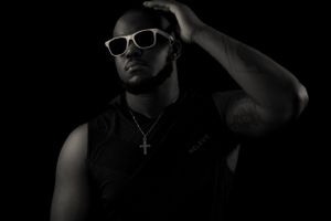 Artistic black and white portrait of person adjusting sunglasses in dark setting.