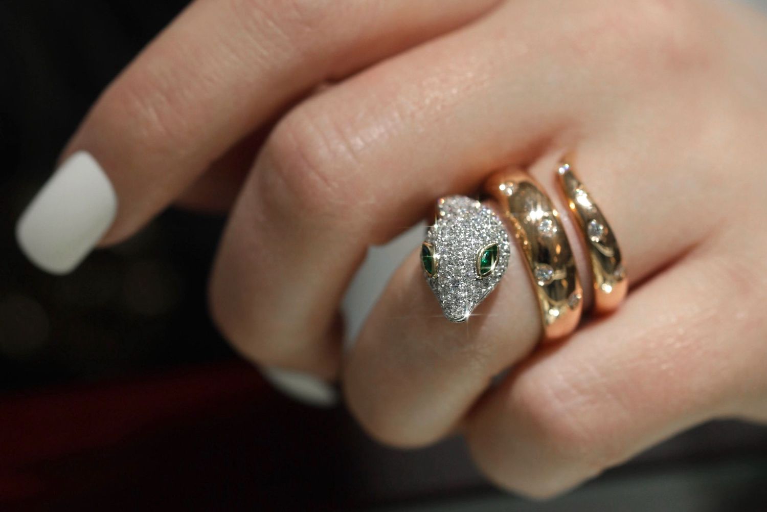 Close-up of elegant diamond and gold statement rings on manicured fingers.