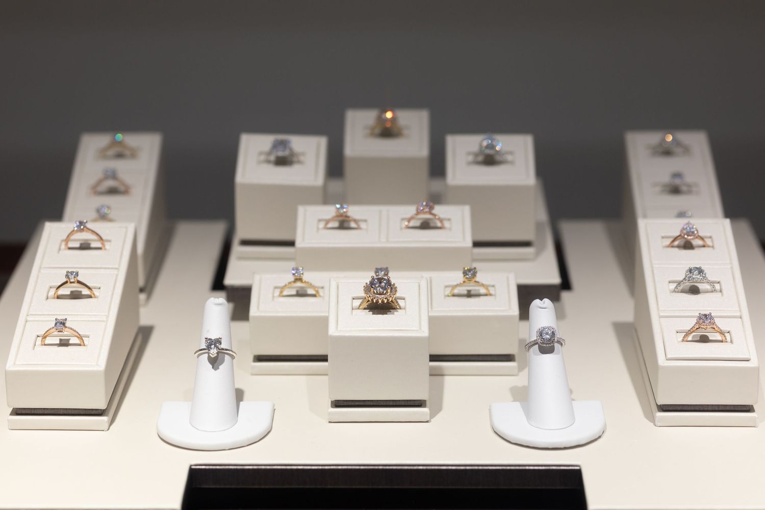 Collection of engagement rings displayed on white pedestals in jewelry store setting.