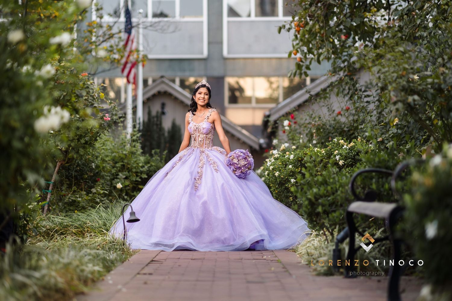 Enchanting portrait of person in lavender ballgown standing on garden path.