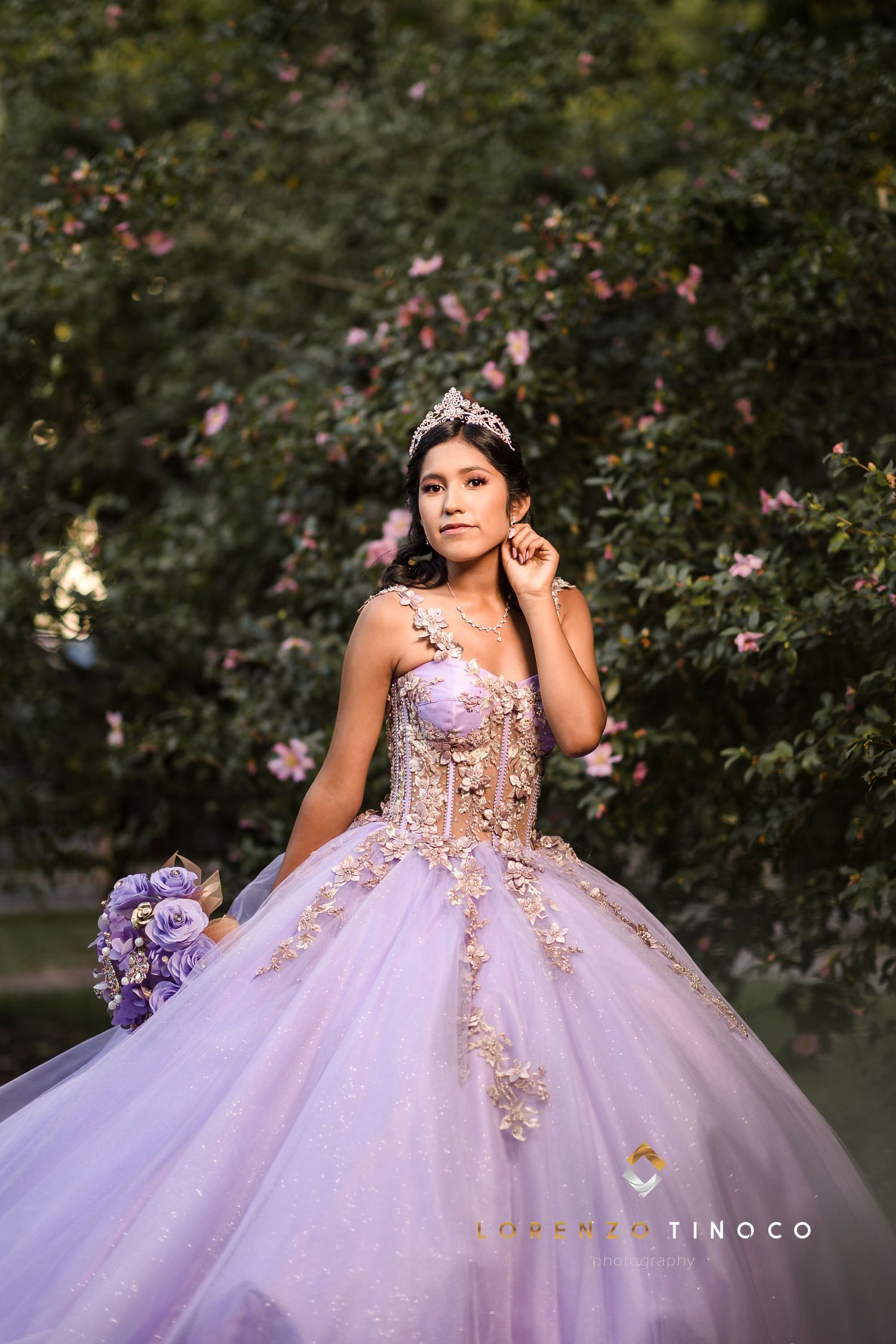 A stunning lavender quinceañera dress with gold embellishments and a matching purple bouquet.