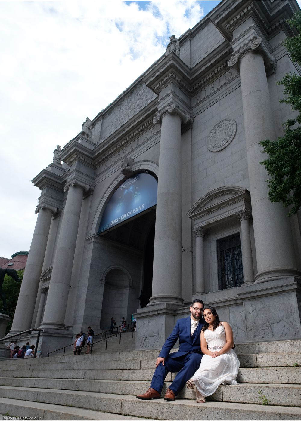 Couple sitting on grand stone steps of historic building.