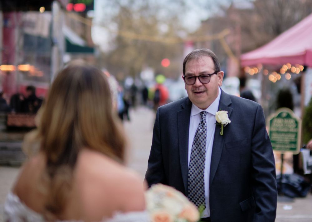 A candid outdoor wedding moment captured on a city street with festive lights.