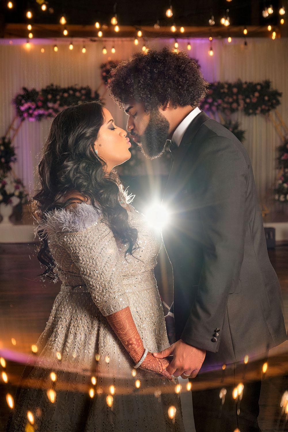 Intimate wedding portrait with dramatic backlighting and string lights.