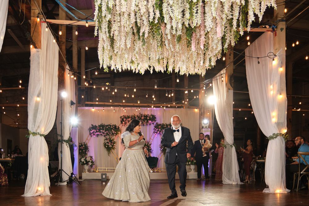 Wedding reception venue decorated with hanging floral installations and elegant string lights.