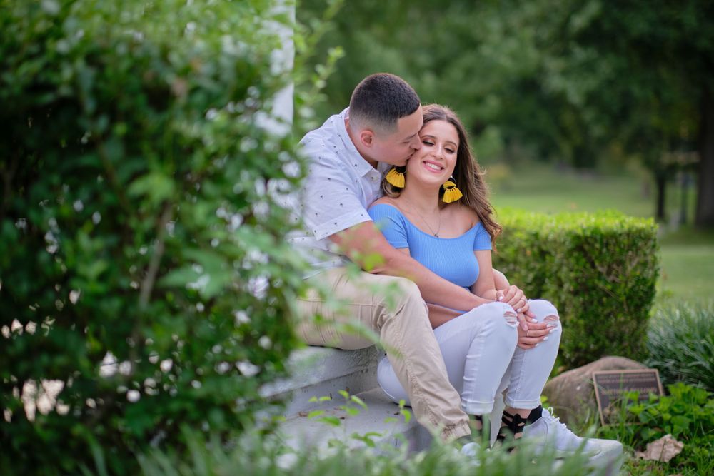 A couple shares an intimate moment in a garden setting.